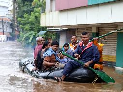 Varias personas cruzan una avenida inundada en una lancha neumática en Kochi, estado de Kerala. EFE/P. Elamakkara