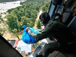 Un soldado del ejército indio distribuye material de socorro para personas varadas en una zona inundada. AP /