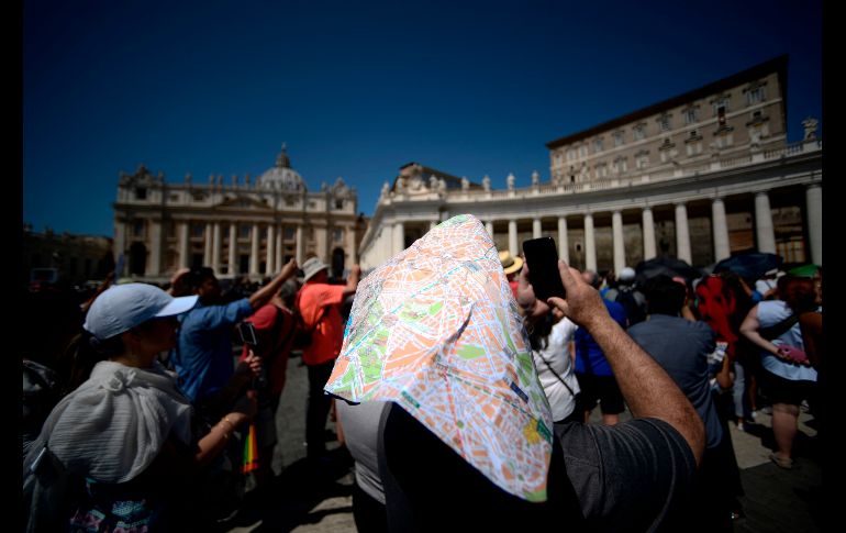 Un hombre se protege del Sol con un mapa mientras toma fotos del Papa, quien se dirige a los fieles en la Plaza de San Pedro, en el Vaticano. AFP/F. Monteforte