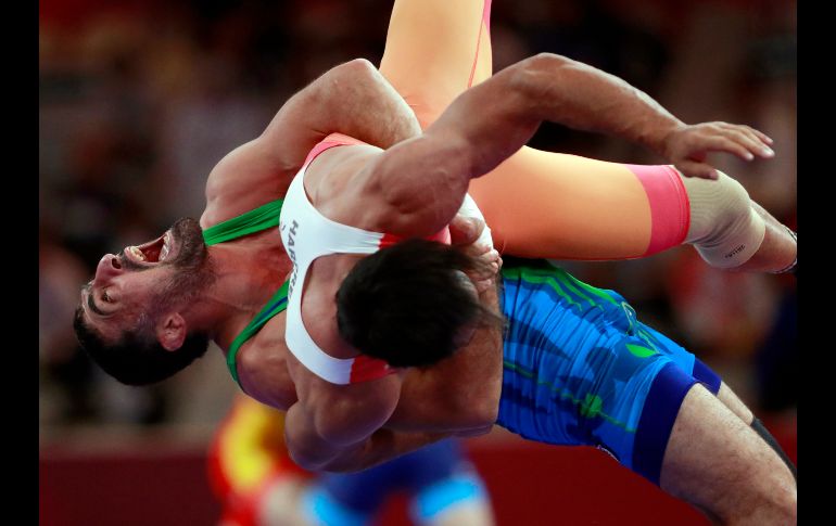 Rustam Assakalov (de azul), de Uzbekistán, compite con Harpreet Singh, de la India, en la semifinal de lucha grecorromana en la categoría de 87 kilos, en el marco de los Juegos Asiáticos en Yakarta, Indonesia. AP/T. Syuflana