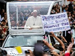 Un activista muestra una pancarta en contra del Papa Francisco (c), mientras recorre las calles del centro de Dublín a bordo del papamóvil. EFE/W. Oliver