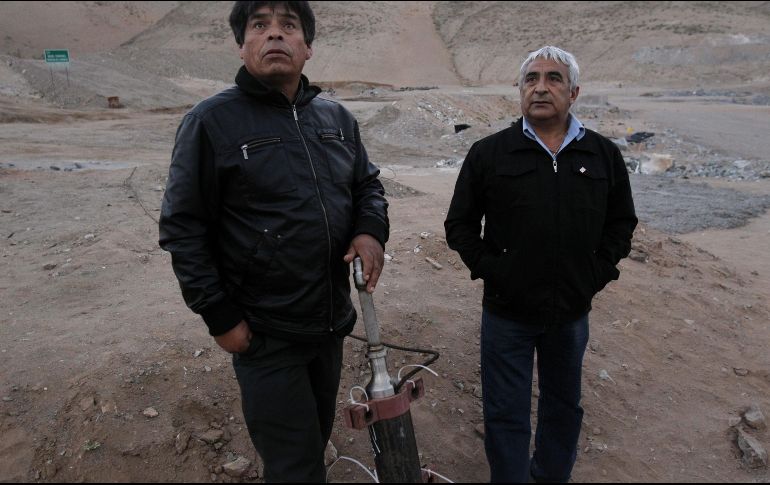 Dos de los mineros muestran la entrada sellada de la sonda por donde recibían alimentos, ropa y accesorios durante los 70 días que permanecieron atrapados. EFE/ARCHIVO