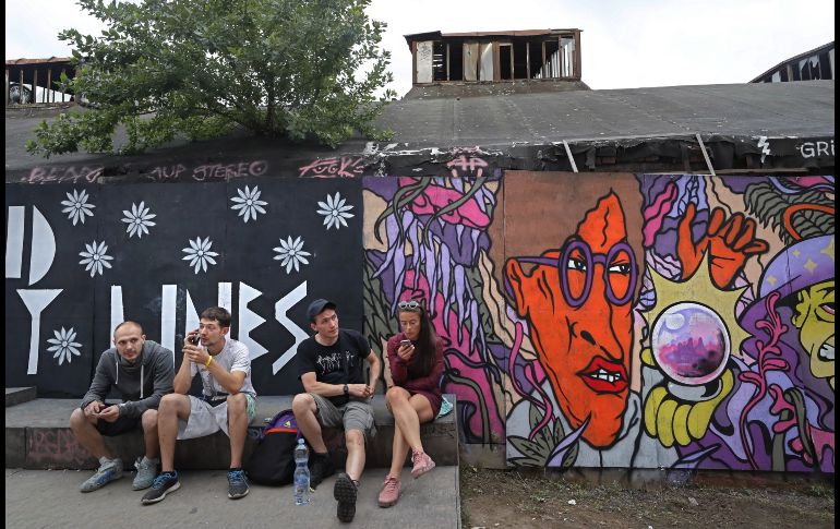 Artistas se ven junto a un grafiti durante la vista previa de la III Bienal de arte urbano 