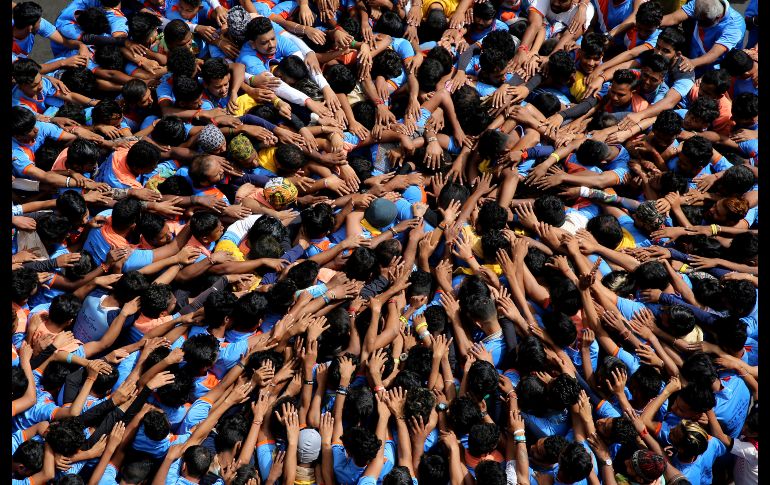 Jóvenes forman una pirámide humana para romper una cazuela de cuajada que cuelga sobre ellos, como parte de las celebraciones del festival 