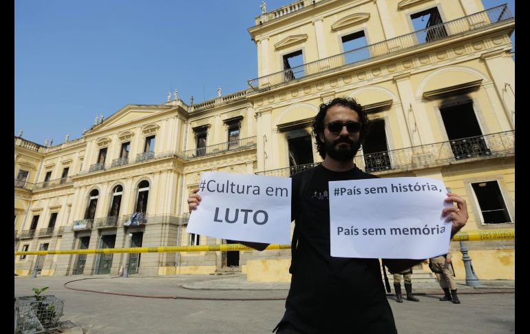 Un hombre muestra un cartel en el que se lee 