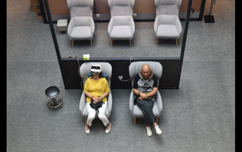 Personas usan productos de un puesto de masajes en un centro comercial en Pekín, China. AFP/W. Zhao