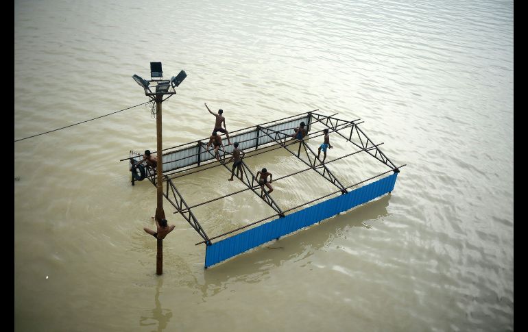 Niños juegan en un baño sumergido en Allahabad, India, mientras se bañan en la orilla del desbordado río Ganges. AFP/S. Kanojia
