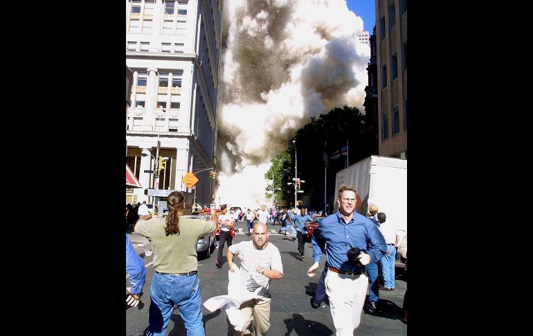 Peatones corren tras el derrumbe de una de las torres. AFP/ARCHIVO