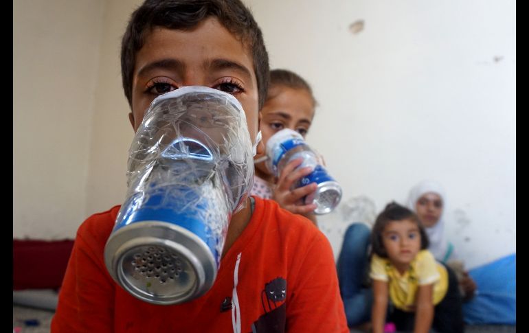 Niños prueban máscaras antigás improvisadas en su casa en Binnish, Siria, en la provincia de Idlib controlada por los rebeldes, como parte de los preparativos para los ataques del régimen sirio y su aliado ruso. AFP/M. Haj Kadour