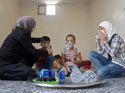 Una mujer le prueba a uno de sus hijos una de las máscaras, elaboradas con materiales reciclados. AFP/M. Haj Kadour