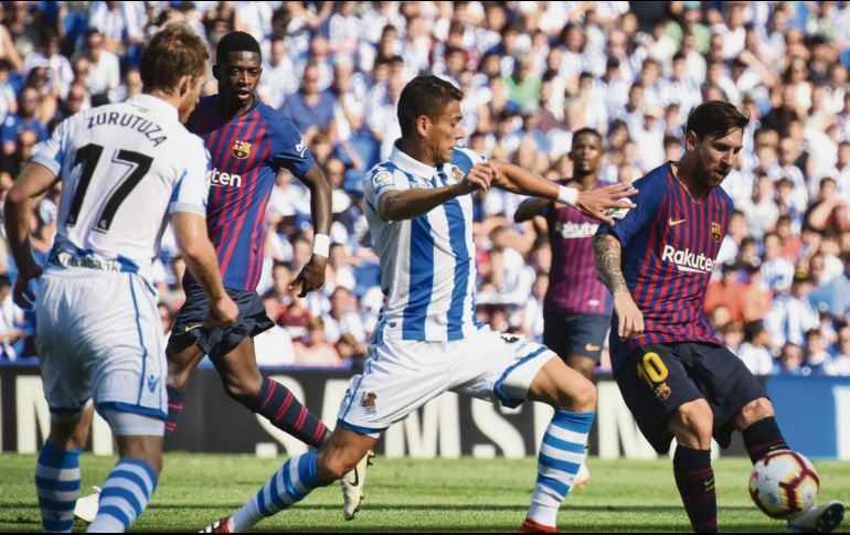 El defensa mexicano Héctor Moreno llega tarde en su intento por despojar del balón a Lionel Messi, en el partido de ayer entre la Real Sociedad y el Barcelona. AP