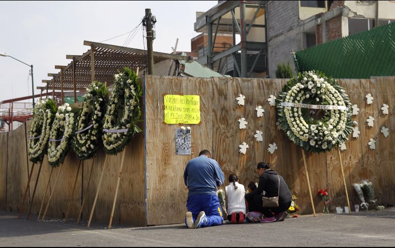 Familiares de algunos de los niños que perdieron la vida en el Colegio Rébsamen durante el terremoto de 2017 oran junto a un muro que resguarda las ruinas de esta escuela. EFE/S. Gutiérrez