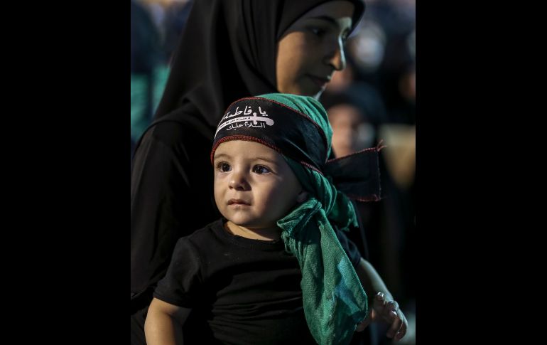 Un partidario de Hezbolá lleva a un niño mientras escucha al secretario general de Hezbollah, Sayyed Hassan Nasrallah, quien pronuncia un discurso a través de un enlace de video, durante la última noche de 