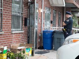 Un policía vigila afuera del inmueble donde se registró el multihomicidio. AP/M. Altaffer