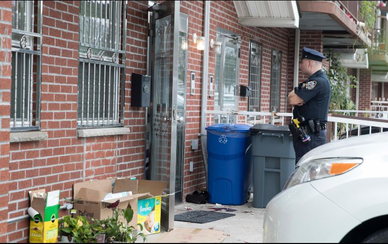 Un policía vigila afuera del inmueble donde se registró el multihomicidio. AP/M. Altaffer