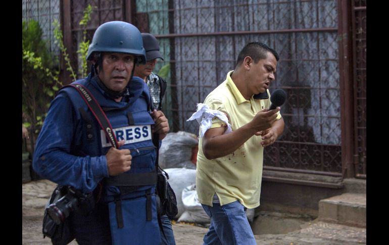 El periodista Wiston Potosme (d) habla por celular luego de ser herido en un brazo durante un tiroteo mientras cubría la marcha 