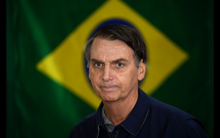 El candidato ultraderechista a la Presidencia de Brasil, Jair Bolsonaro, pasa frente a una bandera nacional al acudir votar en Río de Janeiro. Brasil realiza la primera vuelta de las elecciones presidenciales. AFP/M. Pimentel