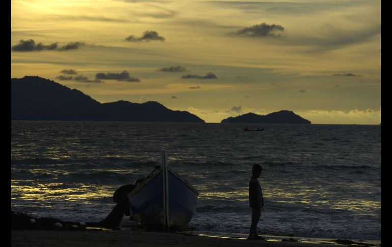 Un niño se ve junto a un bote pesquero en la playa de Banda Aceh, en Indonesia. AFP/C. Mahyuddin