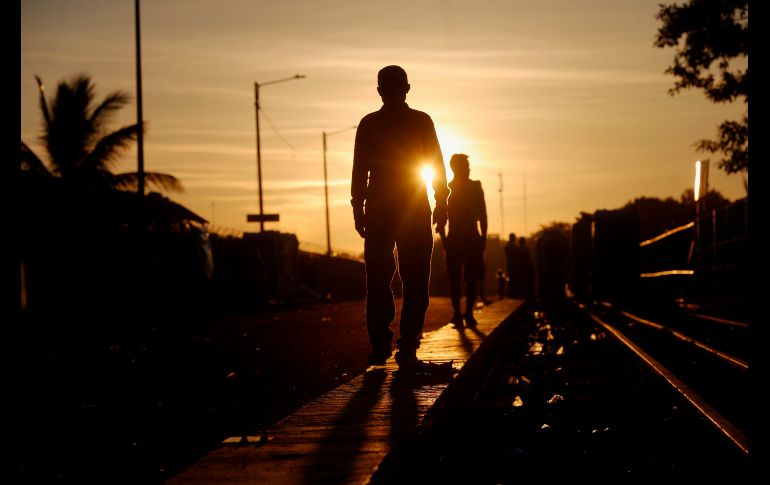 Migrantes hondureños caminan al amanecer en el puente que divide México de Tecún Umán, Guatemala. EFE/E. Biba