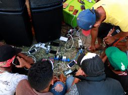 Cientos de hondureños recargan energía (para el cuerpo y para sus celulares) en Oaxaca, una de las escalas de la caravana migrante que va a Estados Unidos. NOTIMEX/F. Estrada