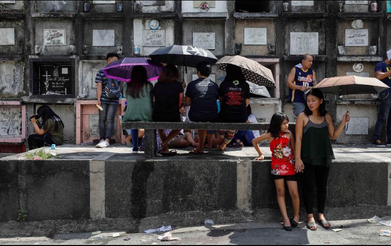Comerciantes vendían flores, velas, comida, bebidas e incluso juguetes entre las tumbas recién lavadas a la multitud de familias que visitaban las sepulturas. EFE/R. Dela Pena