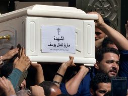 Durante un funeral, un sacerdote y miembros de la congregación oraron y cantaron sobre una fila de ataúdes blancos. AP / A. Nabil
