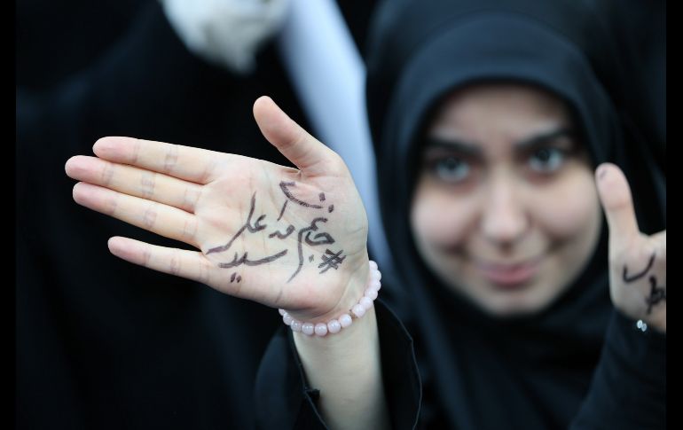 Una joven muestra un mensaje que reza 