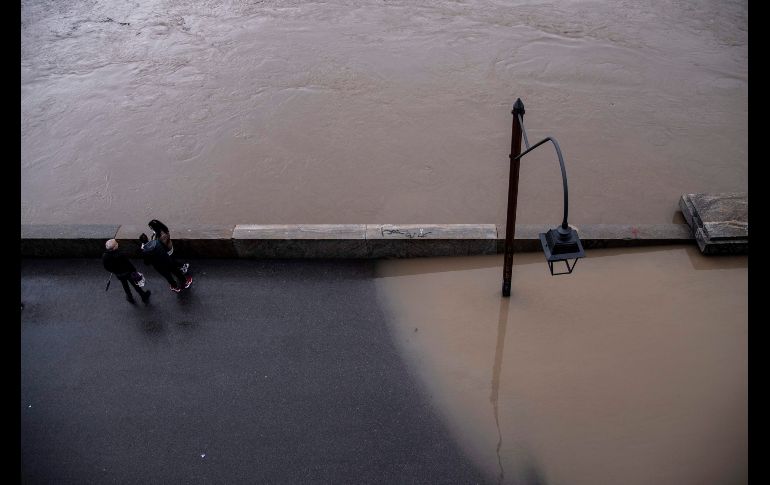 Personas se paran junto a una zona inundada por desbordamientos del río Po en Turín, Italia. AFP/M. Bertorello