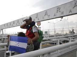 Padre e hijo que viajan en la avanzada del grupo de migrantes cruzan un puente peatonal en el ingreso oriente de la ciudad. EL INFORMADOR / F. Atilano