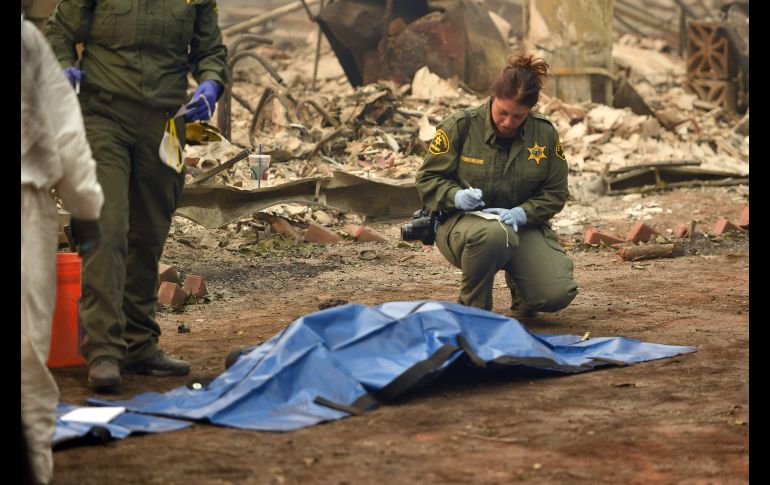 Una oficial marca un cuerpo encontrado en el vecindario Holly Hills de Paradise.