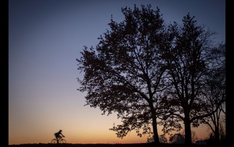 Un ciclista circula a orillas del lago Werde al amanecer en Bremen, Alemania. EFE/F. Strangmann