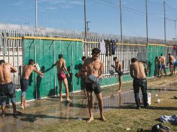 Centroamericanos aprovechan los primeros rayos de Sol para asearse en un refugio temporal en Tijuana. AP