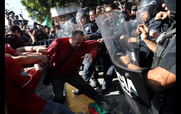 Manifestantes se enfrentan con policías que impiden su avance.