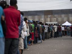 Migrantes centroamericanos hacen fila para buscar comida fuera de un refugio en Tijuana. AFP / P. Pardo
