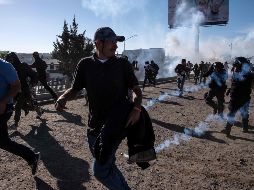 Centroamericanos corren a lo largo del río Tijuana después de que la patrulla fronteriza de Estados Unidos lanzó gas lacrimógeno desde la distancia para dispersarlos. AFP/G. Arias