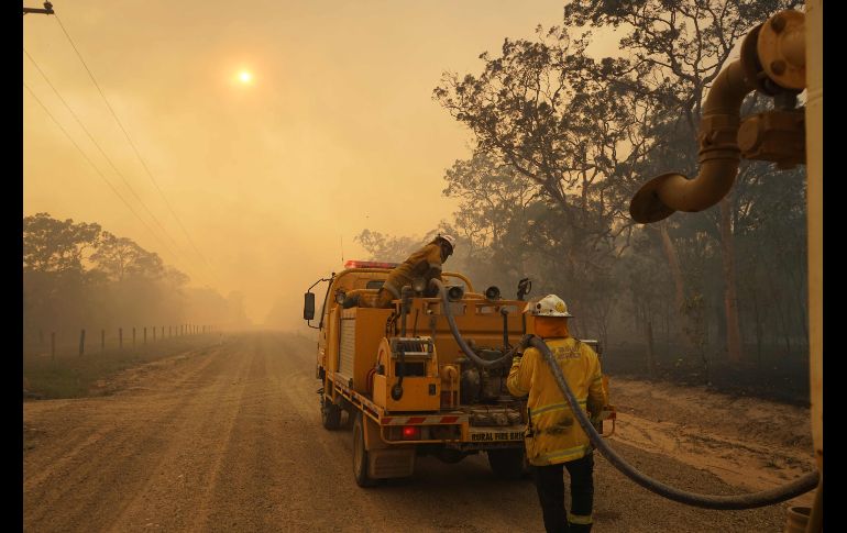 Bomberos rellenan un tanque de agua en el parque nacional Deepwater en Australia. Miles de habitantes han sido evacuados en el estado de Queensland debido a incendios forestales. AFP/R. Griffith