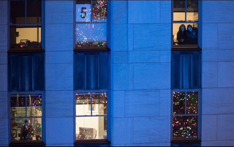 Dos mujeres miran la ceremonia a través de las ventanas de un edificio. AP/M. Altaffer
