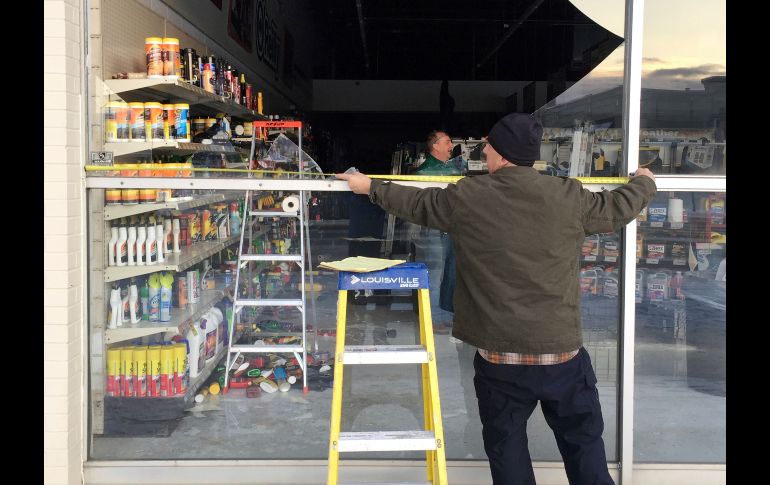 Las sacudidas destrozaron ventanales e interrumpieron el servicio eléctrico. Un habitante mide una ventana que se quebró en una tienda de autopartes en Anchorage.