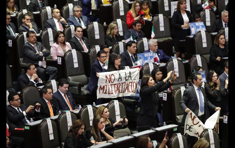 Una legisladora extiende una manta con la leyenda 