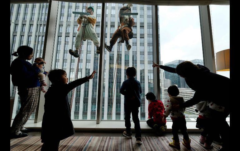 Trabajadores limpian vidrios en un edificio en Tokio, Japón, con disfraces de perro, que representa el año que termina, y de un jabalí, del año que viene. AFP/K. Nogi