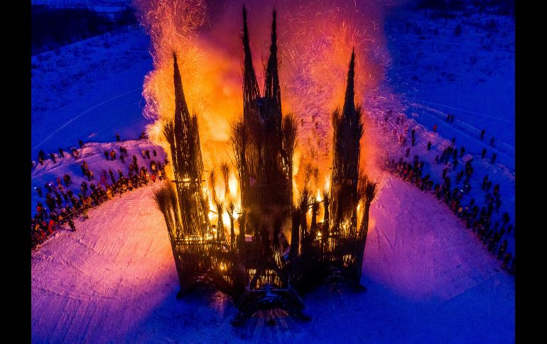 Toma aérea de la quema de una estructura de 30 metros en forma de un edificio gótico, hecha con escombros y ramas pequeñas por el artista ruso Nikolay Polissky, durante la celebración de la Maslenitsa en Nikola-Lenivets, Rusia, el 17 de febrero. La Maslenitsa despide al invierno con la quema de una efigie de gran tamaño. AFP/D. Serebryakov