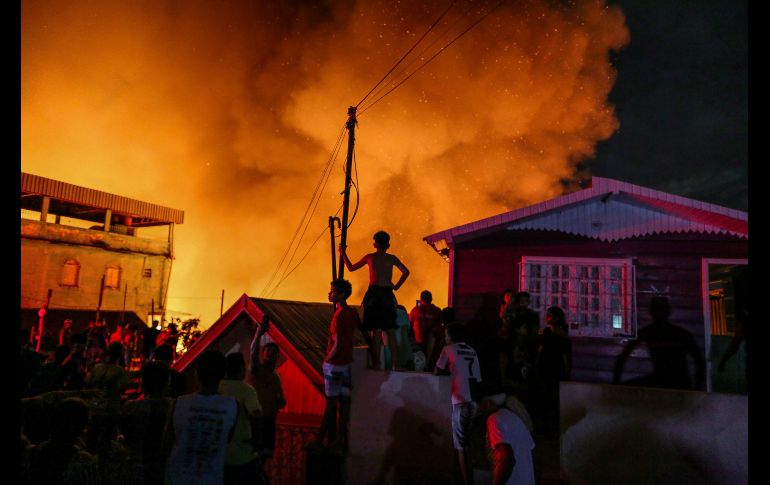 Personas observan mientras los bomberos combaten el fuego.