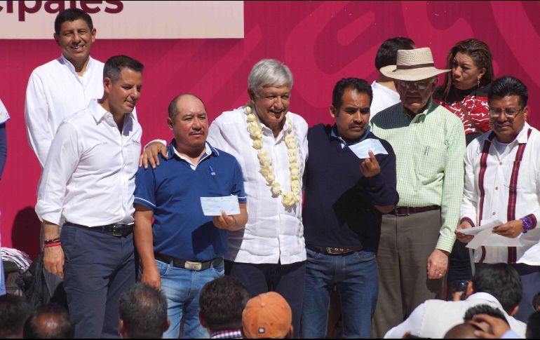 El presidente Andrés Manuel López Obrador (centro) durante la firma del acuerdo del Programa de Pavimentación de Caminos a Cabeceras Municipales en San Juan Evangelista Analco. SUN