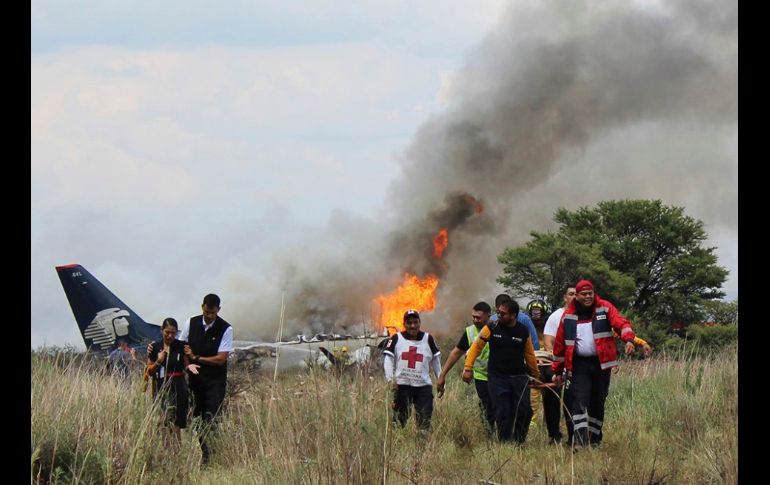 Rescatistas cargan a un herido luego de que un avión se accidentara tras el despegue en el aeropuerto de Durango,  el 31 de julio. De las 103 personas que viajaban a bordo del avión, más de 20 resultaron con lesiones. AP/Cruz Roja de Durango