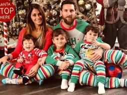 La familia está sentada frente a un enorme árbol de Navidad y un Papá Noel. ESPECIAL