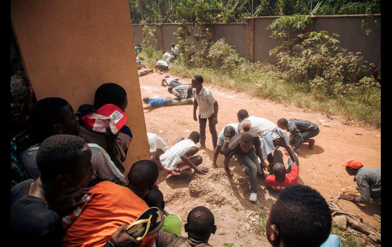 Manifestantes huyen del fuego de militares afuera de las oficinas de la comisión electoral en Beni, República Democrática del Congo, durante una protesta en contra del aplazamiento de las elecciones en la región. AFP/A. Huguet