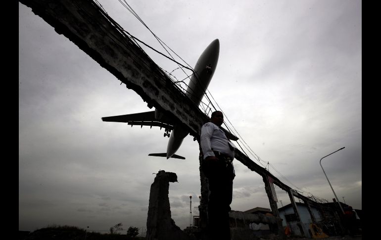 Un avión aterriza mientras un oficial de seguridad filipino monta guardia en el Aeropuerto Internacional Ninoy Aquino de Manila, Filipinas. EFE/ F. Malasig