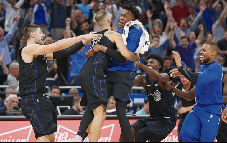 Evan Fournier (centro) es felicitado por sus compañeros después de conseguir la canasta del triunfo para Orlando. AP