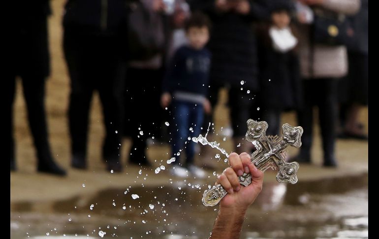Un nadador levanta la cruz que lanzó un sacerdote para bendecir las aguas en Famagousta, en la costa este de Chipre.