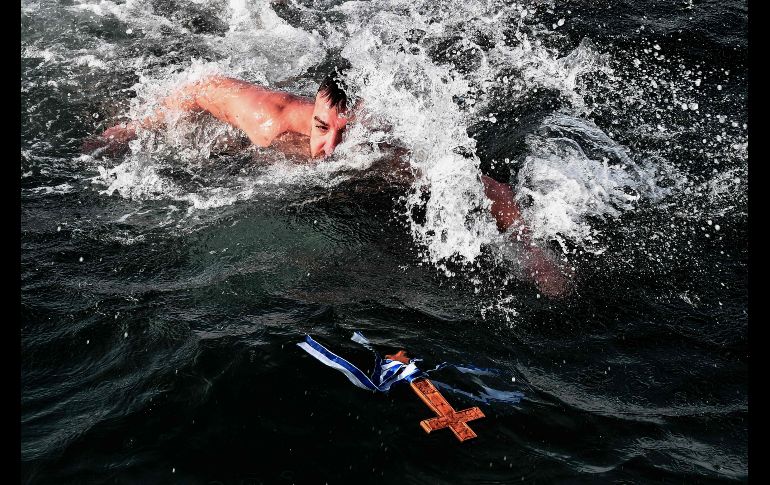 Como parte de la tradición ortodoxa en la celebración de la Epifanía, un sacerdote arroja una cruz de madera al agua y fieles se lanzan para encontrarla. En aguas del puerto griego de Tesalónica.